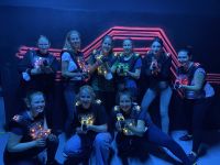 Die Leiterinnen der PSG Friedberg halten nach ihrem Lasertag-Ausflug zufrieden ihre Lasertag-Pistolen und grinsen in die Kamera.